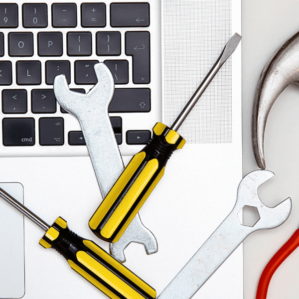 How to Design Digital Infrastructure for Training. Wrenches, screwdrivers, and a hammer laying next to a laptop keyboard.